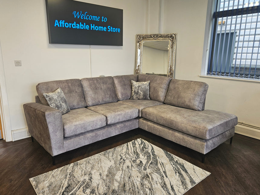 Gray sectional sofa in a room with a mirror and television displaying 'Welcome to Affordable Home Store'.
