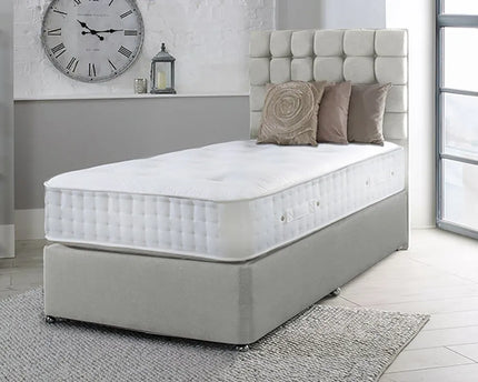 A single divan bed with a grey upholstered headboard and a white mattress, 