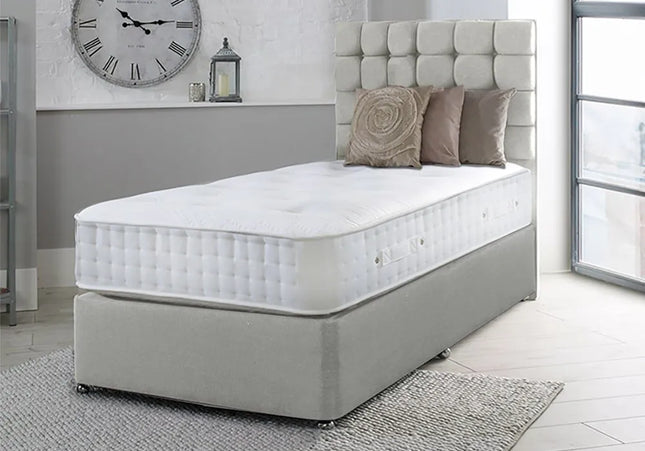 A single divan bed with a grey upholstered headboard and a white mattress, 