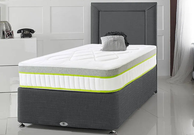 A single divan bed with a gray fabric upholstered headboard and a white mattress with yellow accents. 