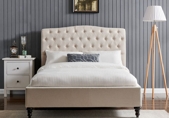 A beige upholstered double bed with a buttoned headboard, wooden feet, 