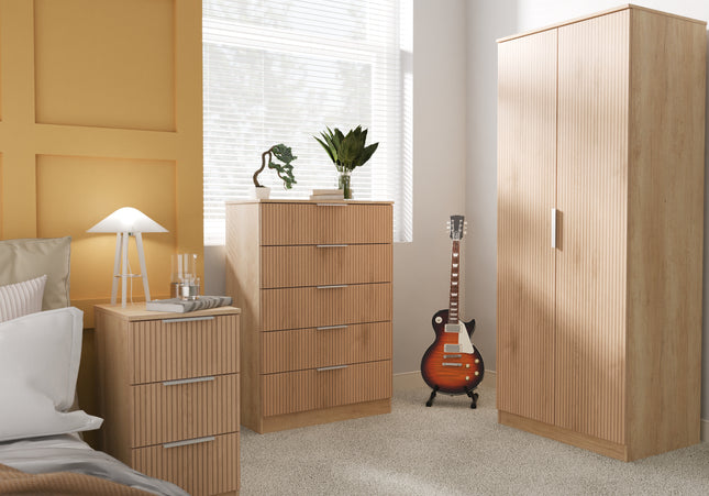 A set of wooden bedroom furniture including a wardrobe, chest of drawers, and bedside table