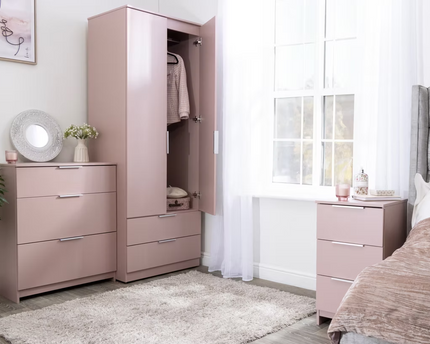 A set of pink bedroom furniture including a wardrobe, chest of drawers, and a bedside table, 
