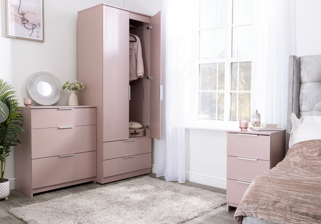 A set of pink bedroom furniture including a wardrobe, chest of drawers, and a bedside table, 