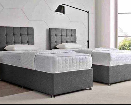 Two single divan beds with gray upholstered headboards and white mattresses.