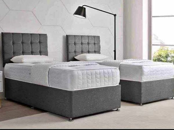 Two single divan beds with gray upholstered headboards and white mattresses.
