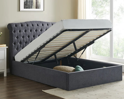 A dark grey Rosa ottoman bed with a button style headboard, the bed is raised showing the storage space beneath, 