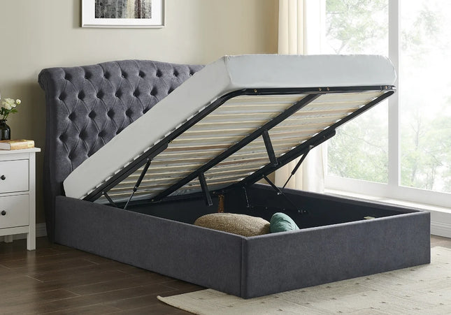A dark grey Rosa ottoman bed with a button style headboard, the bed is raised showing the storage space beneath, 