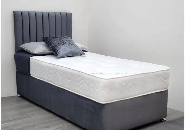 A single divan bed with a gray upholstered headboard and a white mattress, set on a gray fabric bed base.